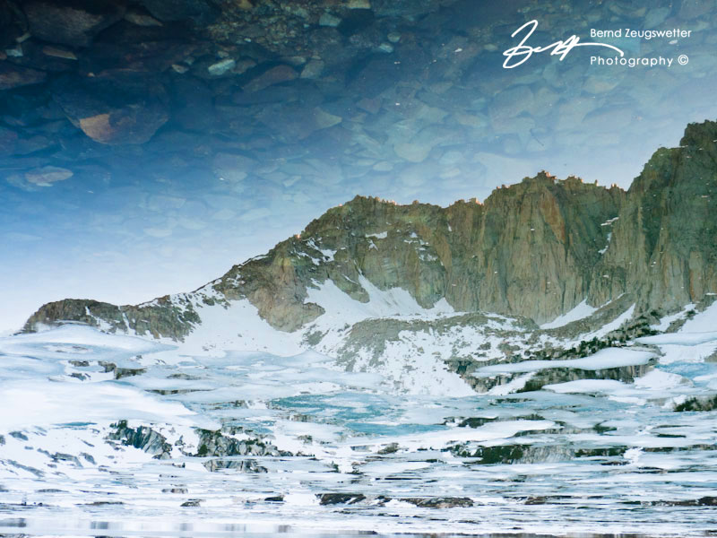 Mountain reflection in icy lake.
