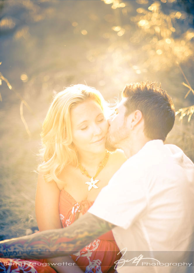 Close-up of engaged couple kissing with setting sun.