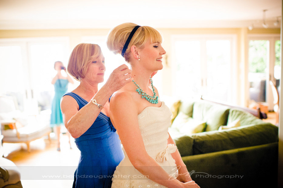 Bride's mother helping bride put on necklace, Santa Barbara.