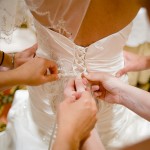 Detail of hands lacing up the wedding gown.