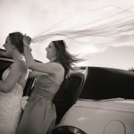 Bridesmaid adjusting the bride's veil in the wind.