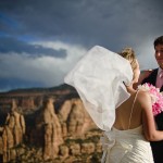 Bride and groom in gale winds overlooking Wedding Canyon, Colo. Nat'l Monument