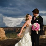 Groom and bride with veil flying in the wind.