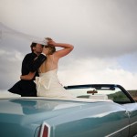 Timeless shot of bride and groom kissing in their convertible.